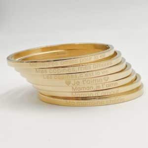 Bracelet jonc en acier inoxydable de couleur dorée composé d’un anneau plein avec une inscription gravée sur le dessus ainsi que sur le dessous