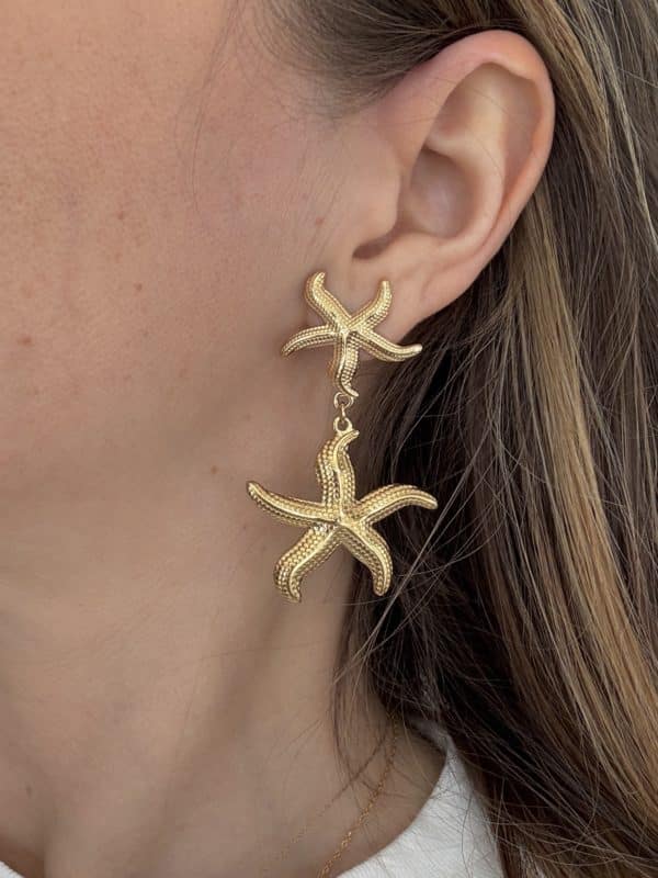Boucles d'oreilles pendantes en acier inoxydable de couleur dorée composées de deux étoiles de mer