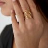 Bague très large sur le doigt composée d'une multitude de fins anneaux et de deux jolis strass blancs