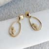 Boucles d’oreilles pendantes en acier inoxydable de couleur dorée composées breloques ajourées avec hippocampes