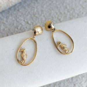 Boucles d’oreilles pendantes en acier inoxydable de couleur dorée composées breloques ajourées avec hippocampes