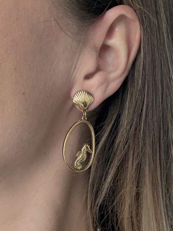 Boucles d’oreilles pendantes en acier inoxydable de couleur dorée composées breloques ajourées avec hippocampes