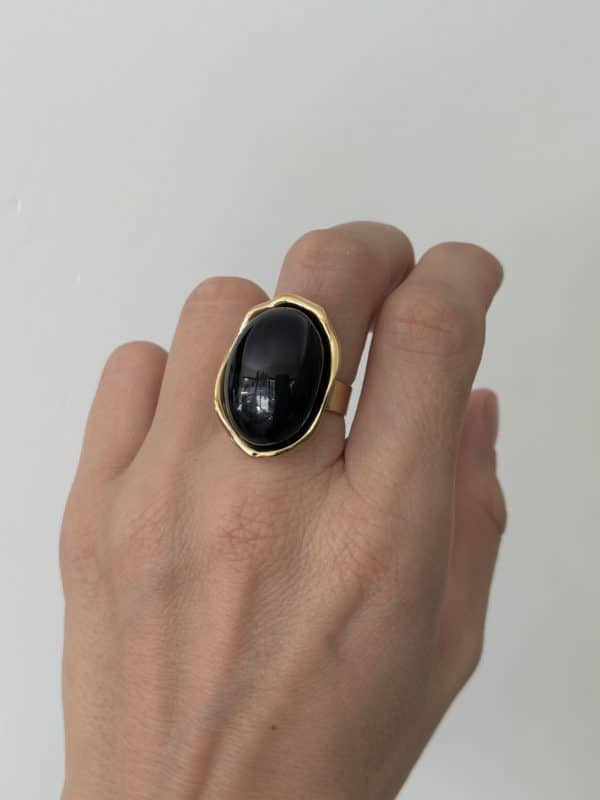 Bague LAUREEN – Bague large avec pierre naturelle d'onyx – Bijou doré en acier inoxydable Bague large  fabriquée en acier inoxydable de couleur dorée. Vous trouverez une pierre naturelle d'onyx en son centre, de couleur noire