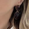 Boucles d'oreilles pendantes en acier inoxydable de couleur dorée. Finitions ambre