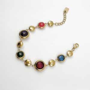 Bracelet assez large en acier inoxydable doré composé d'une ribambelle de strass multicolores et de breloques en acier inoxydable doré