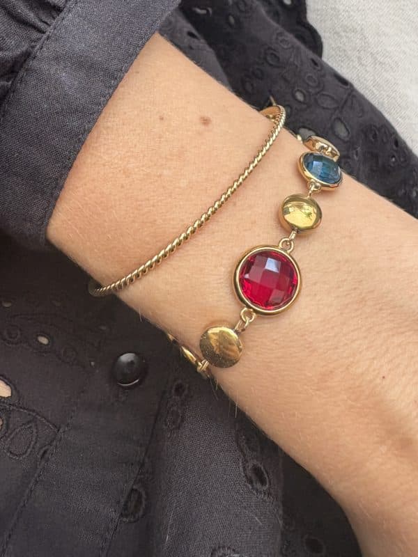 Bracelet assez large en acier inoxydable doré composé d'une ribambelle de strass multicolores et de breloques en acier inoxydable doré