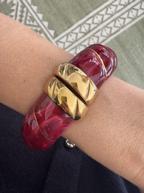 Bracelet torsadé de type jonc, manchette, en acier inoxydable et acétate de couleur framboise.