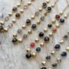 Collier assez large en acier inoxydable doré composé d'une ribambelle de strass et de breloques en acier inoxydable doré