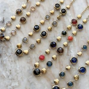Collier assez large en acier inoxydable doré composé d'une ribambelle de strass et de breloques en acier inoxydable doré