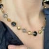 Collier assez large en acier inoxydable doré composé d'une ribambelle de strass et de breloques en acier inoxydable doré