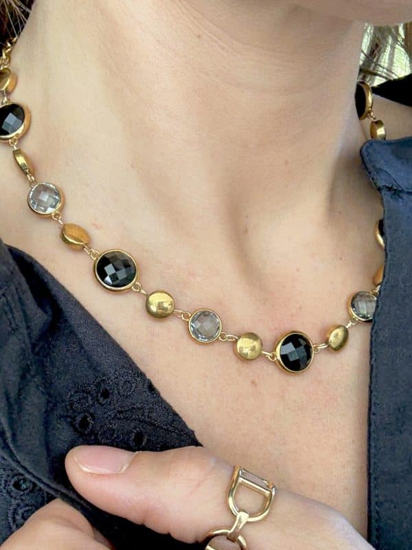 Collier assez large en acier inoxydable doré composé d'une ribambelle de strass et de breloques en acier inoxydable doré