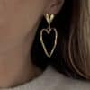 Boucles d'oreilles pendantes en acier inoxydable de couleur dorée Composées d'une puce d'oreille en forme de coeur lisse ainsi que d'un pendentif en forme de coeur martelé