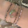 Bracelet monté sur élastique doré à noeuds coulants et petit pendentif oval de pierre naturelle 