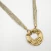 Collier composé d'une multitude de fins cordons dorés aisni que d'un large pendentif de forme ronde