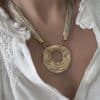 Collier composé d'une multitude de fins cordons dorés aisni que d'un large pendentif de forme ronde