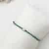 Joli bracelet fait main, ce bijou est composé de petites perles de zirconium vert émeraude ainsi que d'une fine perle d'eau douce véritable et finitions en acier inoxydable doré