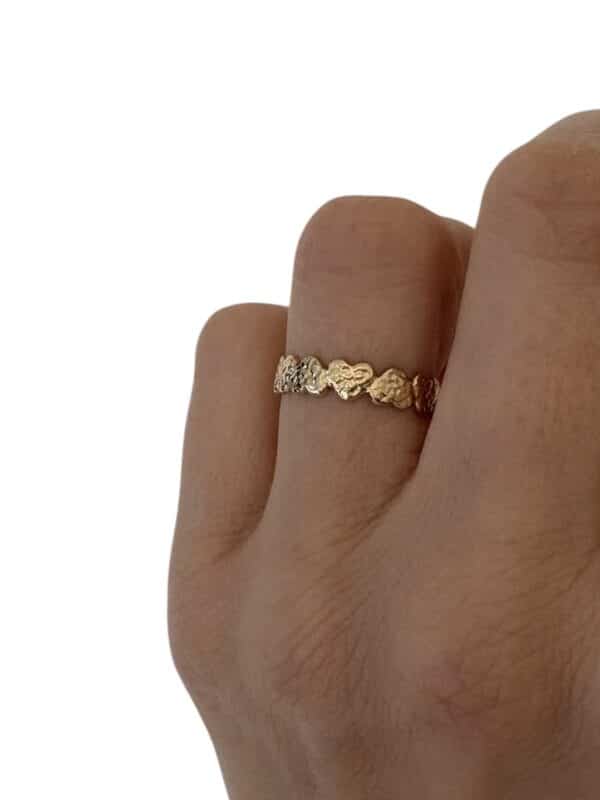 Bague fine composée d'une ribambelle de petits coeurs martelés en acier inoxydable de couleur or
