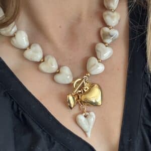 Collier composé d’une succession de coeurs en résine beige avec pampilles en forme de coeurs en résine et acier inoxydable