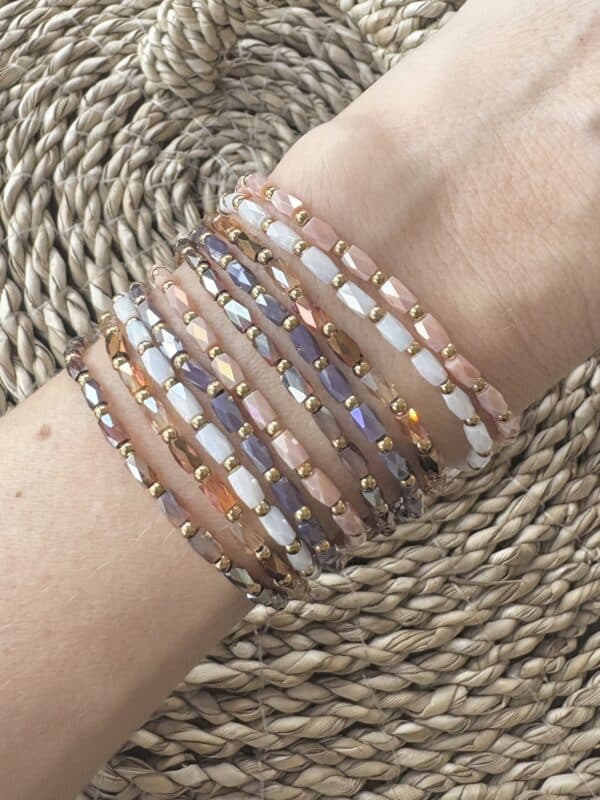 Bracelet monté sur élastique composé de perles de verre de couleur blanc et de petites billes en acier inoxydable de couleur dorée 