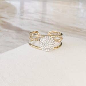 Ce bijou est composé de trois très fins anneaux ajustables et, en meur centre, d’un petit rond serti d'une multitude de strass blancs