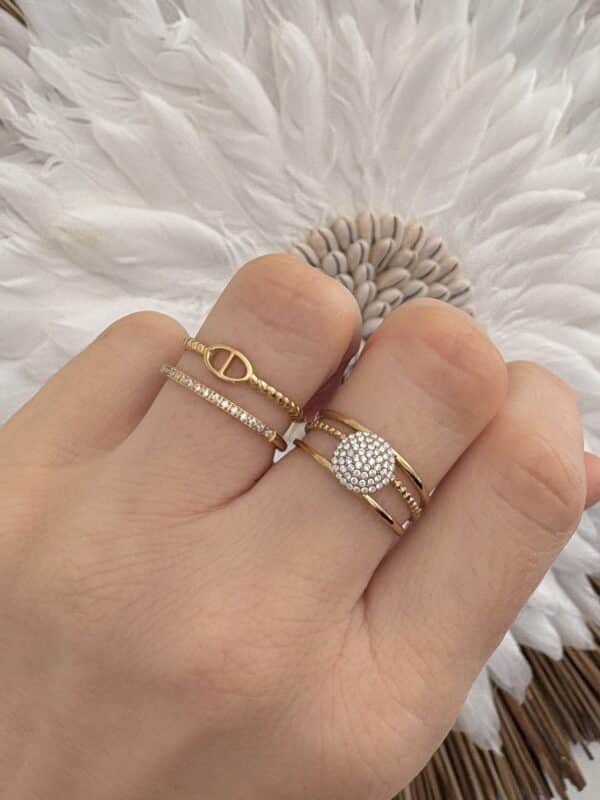 Ce bijou est composé de trois très fins anneaux ajustables et, en meur centre, d’un petit  rond serti d'une multitude de strass blancs