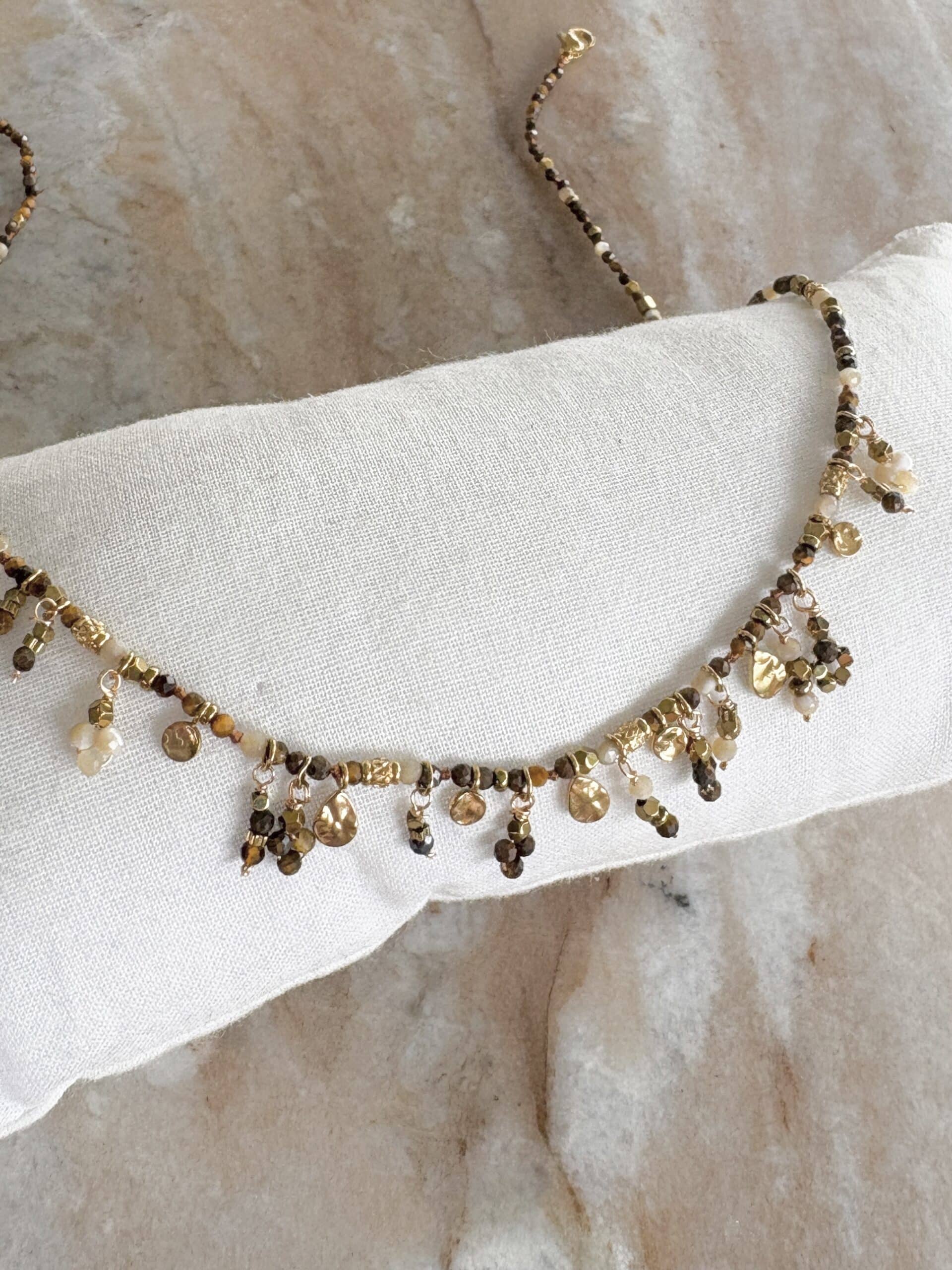 Collier très fin en acier inoxydable doré avec petites pampilles, breloques en acier inoxydable et perles de pierres naturelles – Bijou en acier inoxydable Collier waterproof extrêmement fin et délicat composées de pierres naturelles de nacre et d'oeil du tigre Collier avec pierres naturelles de grande qualité, sélectionnées avec soin Ce bijou se portera aisément seul ou en accumulation pour un look plus travaillé: vous pouvez découvrir notre collection complète de colliers en cliquant juste ici Dimensions: 40 cm au plus court - 45 cm au plus long : chainette de réglage Les petits plus: Ce bijou peut se porter en parure, il existe effectivement le bracelet BOHEME assorti, à découvrir en cliquant ici Ce collier existe dans une multitude de couleurs et de pierres naturelles: découvrez les en suivant ce lien L’acier inoxydable est un matériau résistant, anti allergènique et sans nickel. Il est également waterproof. Vous pouvez donc garder vos bijoux en toutes circonstances