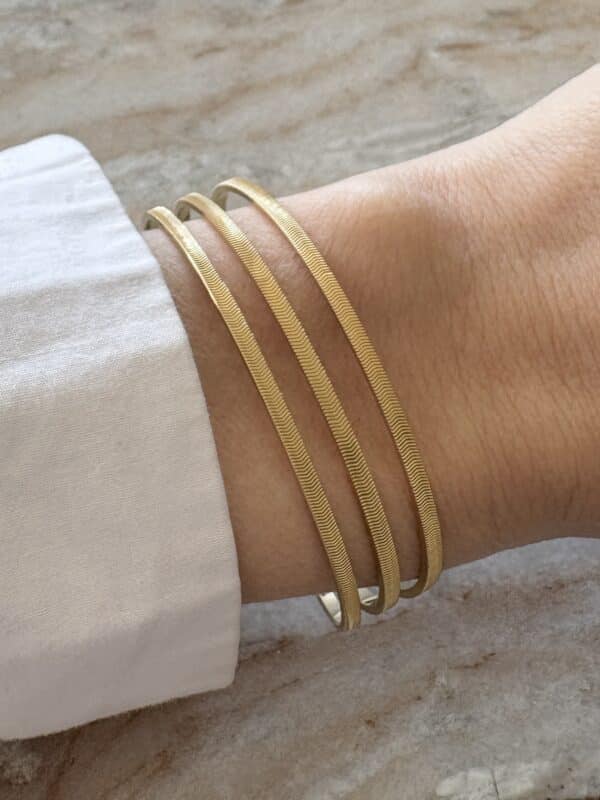 Bracelet manchette jonc en acier inoxydable doré doté de trois rangs finement ciselés