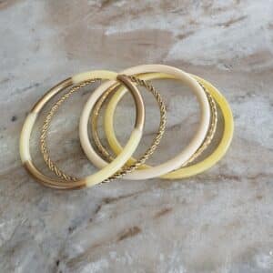 Lot de trois joncs en résine dans les tons de beige et jaune, beurre et deux joncs en acier inoxydable doré plus ou moins ciselés – Bijou vintage