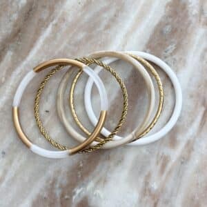 Lot de trois joncs en résine dans les tons de beige et blanc et deux joncs en acier inoxydable doré plus ou moins ciselés