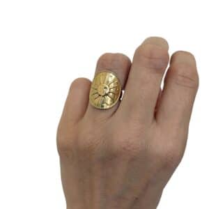Bague assez large sur le doigt avec joli soleil au large sourire ciselé sur son dessus